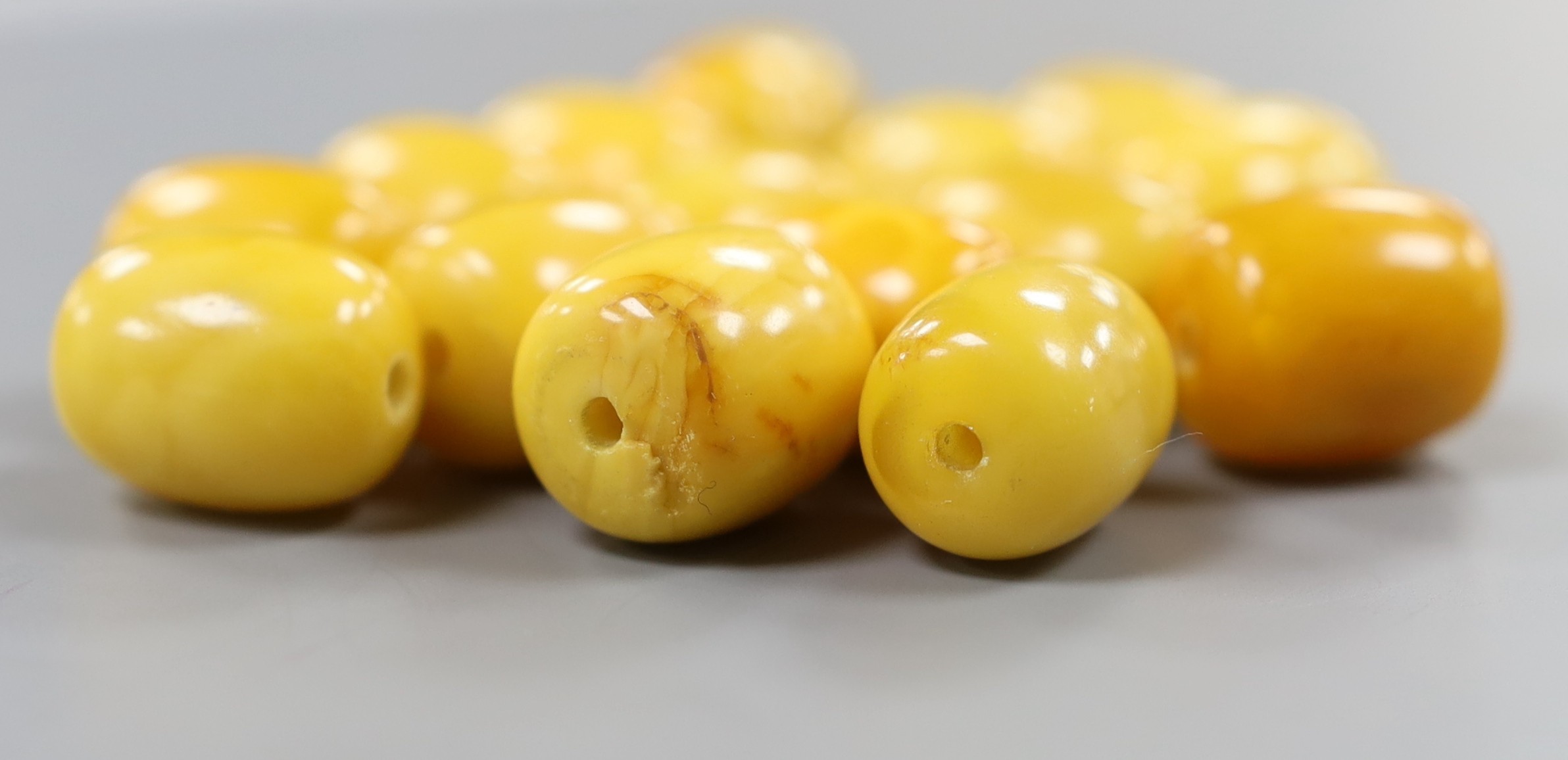 A group of fifteen loose drilled amber beads, 46 grams.
